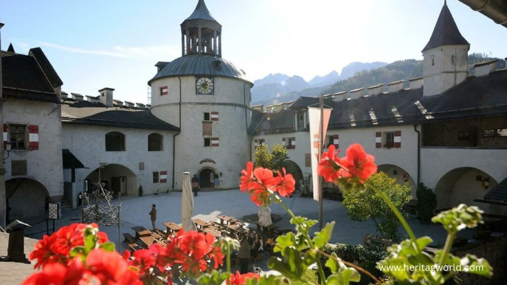 a building with a bell tower and red flowers